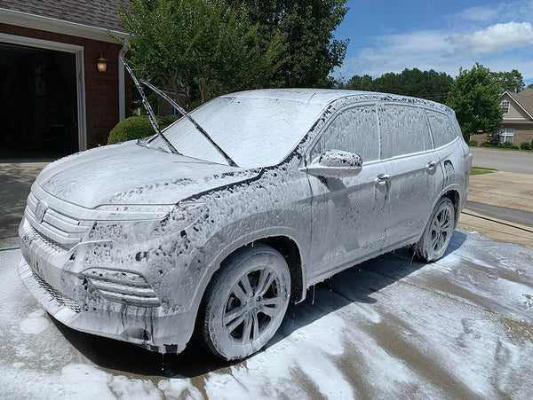 An SUV covered in Pink Car Shampoo from a foam cannon