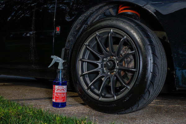 Car wheel with a bottle of car wax spray next to it on a driveway