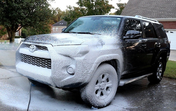 An SUV being covered in Showcar Wash-N-Wax soap using a foam cannon